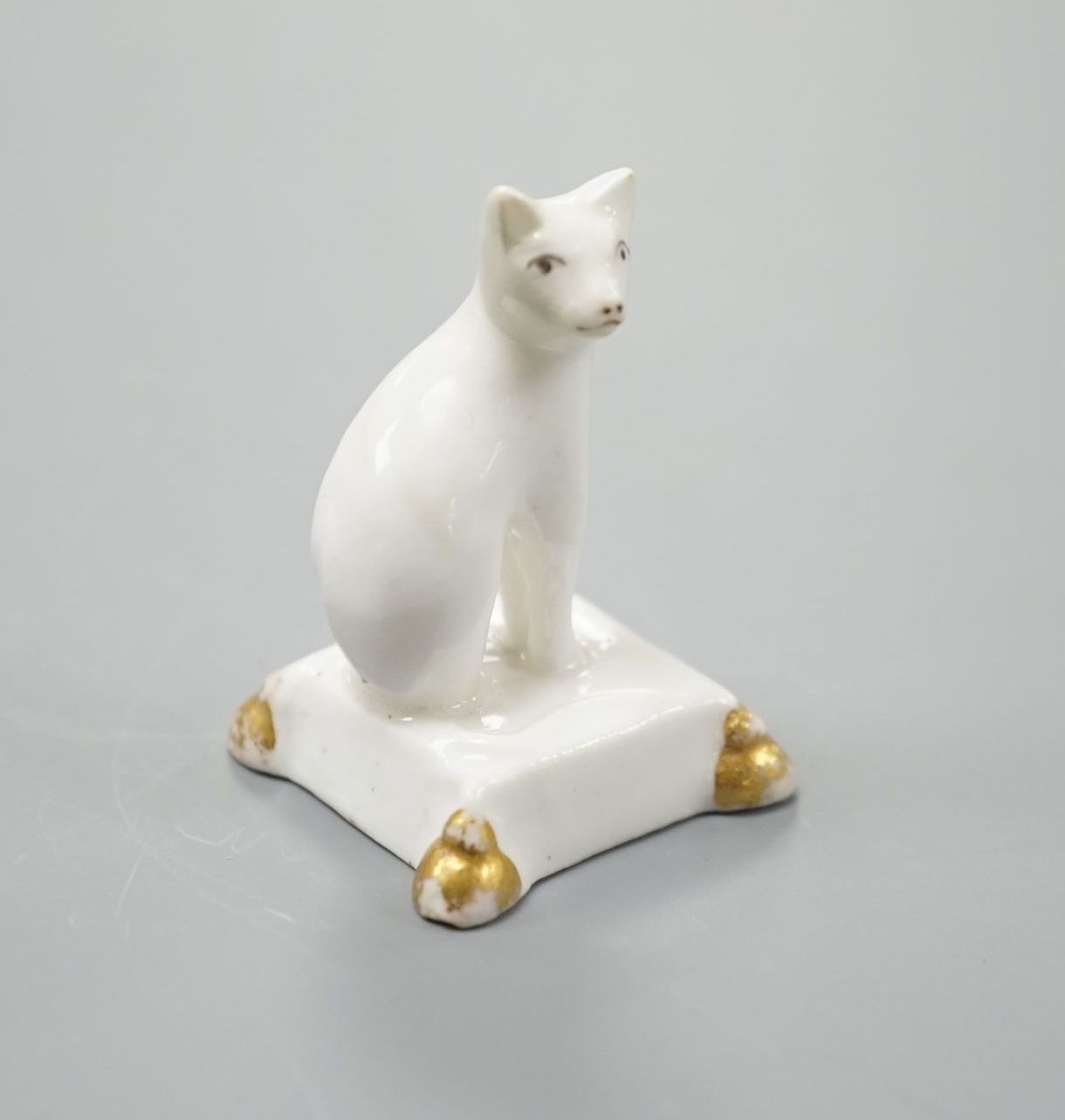 A rare English porcelain model of a cat seated on a cushion base, possibly Derby, c.1820-30, 4cm high, Provenance: Dennis G.Rice collection
